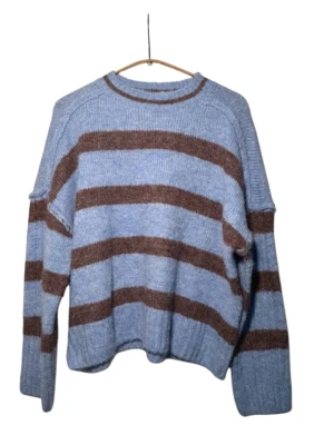 Blåbrun randig stickad tröja - Mysig stickad tröja i ljusblått med breda bruna ränder. Tröjan har avslappnad passform, rund halsringning och ribbade muddar vid ärmslut och nederkant. Perfekt för lager på lager och chill dagar. Materialet känns mjukt och skönt mot huden.