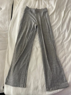 Gråmelerade utsvängda leggings - Säljer ett par gråmelerade leggings med utsvängda ben och hög midja. Mjukt och stretchigt material som sitter skönt på kroppen. Perfekta till en avslappnad look eller när du vill vara extra bekväm.