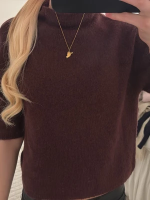 Vinröd stickad topp med kort ärm - Mysig vinröd stickad+ topp med korta ärmar och hög hals. Tröjan har en rak passform och är perfekt för lager på lager soppar. Materialet ser mjukt och lite luddigt ut, vilket ger en avslappnad vibe.158/164 storlek men passar bra till xs,s