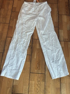 Vita linnebyxor i nyskick - Säljer ett par vita linnebyxor med avslappnad passform och raka ben. Byxorna har resår i midjan och är tillverkade i ett lätt och luftigt linnetyg. Dem är helt nytt sick och är aldrig använda. Säljer pågrund av att dem ej passade. Dem är storlek 170 från Gina Young. 