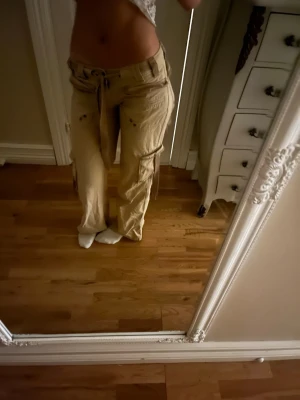 Låg midjade beiga cargobyxor  - KONTAKTA INNAN DU KÖPER! 💕Low rise beiga cargobyxor med vida ben och flera fickor på sidorna. Byxorna har slitna detaljer och knytband i midjan. Säljer eftersom jag inte har använt  dom men skitsnygga o äkta lowrise! Pris kan absolut diskuteras 