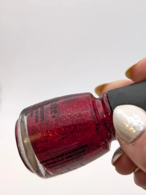 Rött glitter nagellack China Glaze 70% kvar - Snyggt rött nagellack från China Glaze med massor av glitter som ger en glansig och festlig finish. Kommer i en klassisk rund glasflaska med svart lock. Perfekt för dig som vill ha extra bling på naglarna!