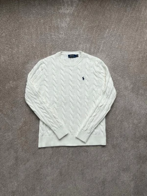 Ralph Lauren Tröja - Kabelstickad vit tröja från Polo Ralph Lauren! Den är skitsnygg men även varm och skön! Den är i väldigt bra skick! Hör av dig vid minsta fråga!