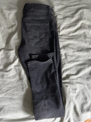 Svarta jeans från Jack & Jones - Säljer ett par svarta jeans från Jack & Jones med klassisk femficksdesign och snygga sömmar på bakfickan. Jeansen har en slim fit och är gjorda i mjukt denim-material som är bekvämt och följsamt. Perfekt för dig som gillar stilrena och tidlösa jeans.
