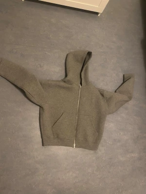 Weekday scuba hoodie  - En stilren grå hoodie med dragkedja framtill och stor huva. Hoodien har långa ärmar och två fickor på sidorna. Tillverkad i mjukt sweatshirtmaterial som är perfekt för chill dagar. Passar dig som gillar enkel och clean stil.