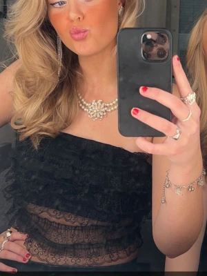 Svart tub topp med spets - Säljer en fin svart tub topp med spets nedtill. Kommer ej till användning längre. Är i storlek L men passar allt från S-L. Superfin fest topp. 