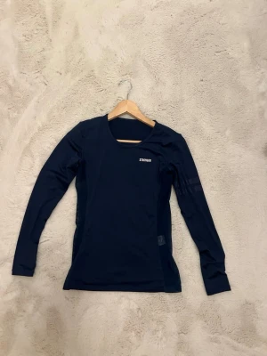 Mörkblå långärmad träningströja Stronger - Snygg mörkblå långärmad träningströja från Stronger med rund halsringning och meshpaneler på sidorna för extra ventilation. Tillverkad i ett stretchigt funktionsmaterial som passar perfekt till träning och sportaktiviteter.