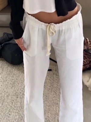 Vita roxy linnebyxor - Snygga vita linnebyxor med avslappnad passform och bred resår i midjan. Byxorna har dragsko för justerbar midja och raka ben. Perfekta för en chill och stilren look. Materialet är luftigt linne som känns svalt och bekvämt. Finns en liten fläck på framsidan och har ett hål i skrevet, se bild. Därav priset, men går säkert att få bort och laga men har inte testat🤍