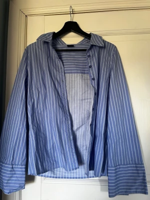 Blåvit randig skjorta  - En skjorta från Gina, andänt några gånger, en knapp är trasig men finns en extra att sätta dit, storlek 40. Alla kläder tvättas innan.