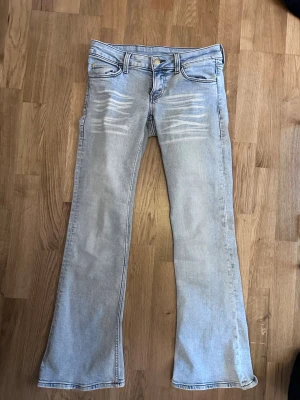 Ljusblå bootcut jeans Cheap Monday - Säljer ett par ljusblå bootcut jeans från Cheap Monday i storlek 28/30  med coola slitningar framtill och en grön logga bak. . Nypris 400 men säljer för 350!  Knappt använda