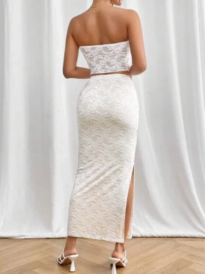 Vit spetsset med tubtop och lång kjol - Säljer ett elegant vitt set med tubtop och lång kjol i spetsmaterial. Toppen är axelbandslös med knytning framtill och kjolen har en hög slits på sidan. Setet har en kroppsnära passform och romantiskt spetsmönster.