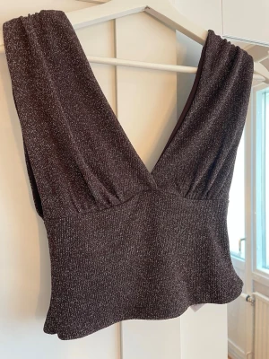 Glittrig mörkbrun croppad topp - Snygg croppad topp i mörkbrunt med glittriga detaljer och djup v-ringning.❤️