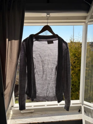 Brunn och stegarde kofta - Säljer en stilren grå brunn och stegarde kofta med långa ärmar och ribbade muddar. Koftan är tillverkad i ett tunt, mjukt material och har en enkel, klassisk design utan knappar. Perfekt att slänga över en t-shirt för en avslappnad look.