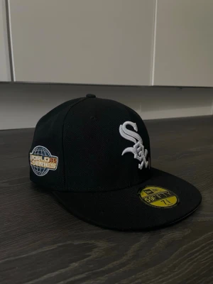 Svart New Era White Sox keps - Säljer en svart New Era 59FIFTY keps med White Sox-logga broderad i vitt framtill och World Series-märke på sidan. Klassisk flat brim och broderad New Era-logga på sidan. Perfekt för dig som gillar sportig streetstyle.