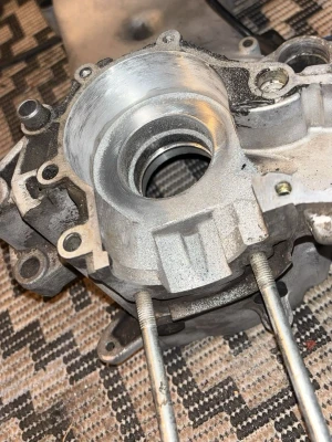 Motorblock i aluminium till moped - Säljer ett motorblock i aluminium, troligen till moped eller liten motorcykel. Blocket har flera fästhål och genomgående bultar, samt en stor cirkulär öppning för vevaxel eller lager. Perfekt för dig som bygger eller renoverar motorer.
