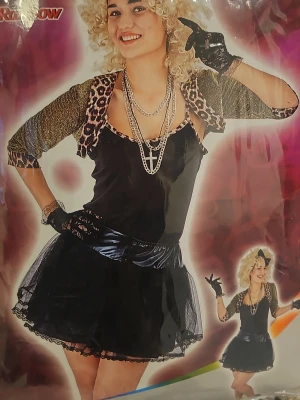 80-tals inspirerat maskeradset - Säljer ett 80-tals inspirerat maskeradset med svart glansig kjol, svart linne, leopardmönstrad bolero, svarta fingerlösa handskar och kedjehalsband. Perfekt för temafest eller cosplay med retrovibbar.