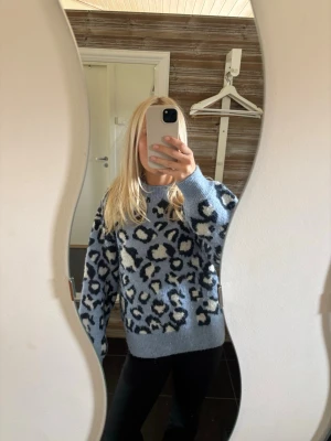 Blå leopardmönstrad stickad tröja - Cool stickad tröja i ljusblått med leopardmönster i svart och vitt. Tröjan har avslappnad passform, rund halsringning och ribbade muddar vid ärmslut och nederkant. Perfekt för dig som vill sticka ut med ett trendigt mönster.Tröjan är i storlek M men passar mig bra som vanligtvis har storlek xs/s💙🩵