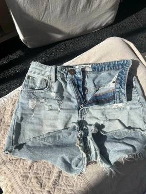 ljusblå lågmidjade shorts från One x one Teaspoon - Säljer mina ljusblå lågmidjade jeansshorts från One x one Teaspoon med slitna detaljer.  köpta för 1200, därav priset. använda två gånger och i nyskick, storlek 24