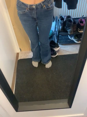 Blå bootcut jeans med hög midja - Säljer ett par klassiska blå bootcut jeans med hög midja och fem fickor. Jeansen har en snygg passform som sitter tajt upptill och släpper ut vid benen. Perfekta till vardagslooken och passar till det mesta. Materialet är mjukt denim i bomull.