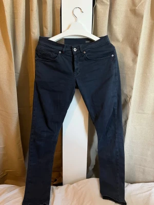 Dondup "George" Skinny Chinos - Toppskick! - Säljer ett par extremt snygga och välvårdade chinos från italienska Dondup, modell George. Byxorna är i en djup mörkblå (navy) färg och har de ikoniska detaljerna som kännetecknar märket. Detaljer: • Modell: George (Skinny fit) • Storlek: W31 / L32 • Passform: Skinny – sitter riktigt snyggt och modernt. • Skick: Toppskick (9/10). Inga slitningar, fläckar eller tappad färg. • Färg: Mörkblå / Navy