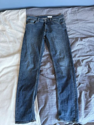 Blå jeans från Tiger of Sweden - Snygga blå jeans från Tiger of Sweden i klassisk rak modell. Jeansen har fem fickor, normal midja och är tillverkade i denim. Perfekta för en stilren och avslappnad look.