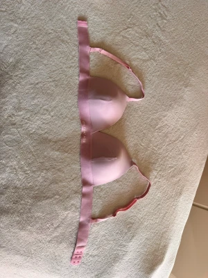 Ljusrosa vadderad bh - Säljer en ljusrosa vadderad bh från On that ass med släta kupor och justerbara axelband. Bh:n har en enkel och stilren design med logotyp på bandet under bysten. Materialet är mjukt och stretchigt för extra komfort. Endast provad