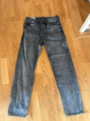 Grå relaxed jeans från H&M - Säljer ett par grå tvättade relaxed fit jeans från H&M. Jeansen har raka ben, klassisk femficksmodell och är tillverkade i bomull. Perfekta för en avslappnad och trendig stil.