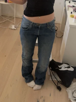 Lee jeans - Säljer ett par klassiska blå bootcut jeans med låg midja och fem fickor. Är lite osäker på storlek men de passar mig som oftast har M/S. Jeansen har en lätt tvättad look och subtila slitningar. Perfekta för dig som gillar en avslappnad och tidlös stil. Materialet är denim i bomull.