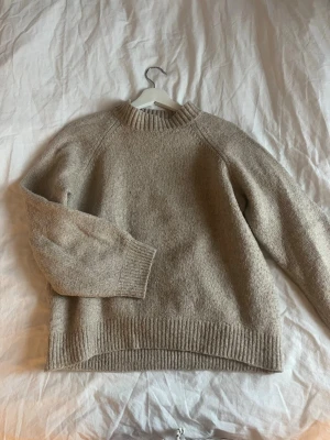 Beige stickad tröja med rund hals - Mysig beige stickad tröja med rund hals och ribbade muddar vid ärmslut, hals och nederkant. Passar st s/m perfekt 