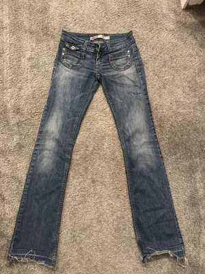 Blå bootcut/mer raka jeans från ONLY - Snygga blå bootcut/raka jeans gammal design från ONLY med slitna detaljer och ljusa tvättade partier. Jeansen har låg midja, lite slitning längdmeter vid hälarna, finns bild. Men annars i väldigt bra skick. Är 164cm.  I byxan på denna design står det W34 L32. Så de passar nog mer en xs i midjan. Säljer pågrund av att de är lite för tajta i rumpa och lår