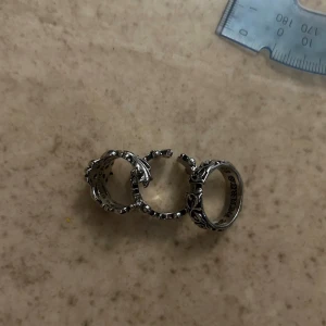 Silverfärgad ring med korsmönster - Cool ring i silverfärgad metall med detaljerat korsmönster runt hela ringen. Ringen har en bred design och tydliga upphöjda detaljer som ger en unik och edgy look. Perfekt accessoar för att lyfta din stil.