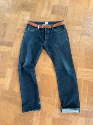 Selvedge jeans - Jag på bilden är 189/ 87kg . Snygga mörkblå jeans med rak passform och klassisk femficksdesign. Perfekta för en avslappnad och stilren look. Materialet är denim i bomull. Säljes utan bälte