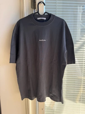 Svart Acne Studios t-shirt - Snygg svart t-shirt från Acne Studios med minimalistisk vit logga på bröstet. Klassisk rund halsringning och korta ärmar. Perfekt basplagg i mjuk bomull som passar till allt.