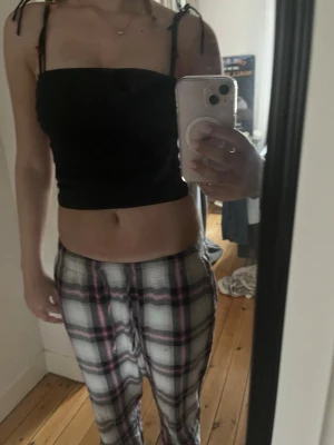 Svart bandeau topp med knytband - Snygg svart bandeau topp med tunna axelband som knyts upptill. Toppen är croppad och har en enkel, stilren design som passar perfekt till jeans eller kjol. 