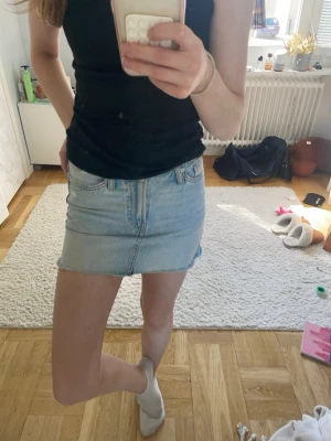 Ljusblå jeanskjol med rå kant - Trendig ljusblå jeanskjol i kort modell med klassisk femficksdesign och rå, fransad nederkant. Perfekt för dig som gillar en avslappnad och cool stil. Kjolen har dragkedja och knapp framtill. Köpt på sellpy men från Bershka🥰