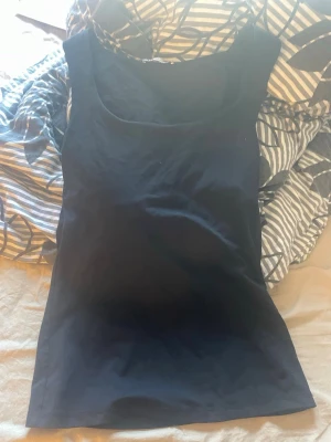 Svart linnetopp från Zara - En stilren svart linnetopp från Zara med rund halsringning. Toppen är ärmlös och har en klassisk, enkel design som passar till många olika outfits. Perfekt för dig som gillar basic plagg med snygg passform.