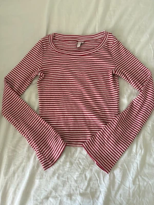 Randig långärmad topp från Nelly - Säljer en croppad långärmad topp från Nelly i rött och vitt med smala ränder. Toppen har rund halsringning och är tillverkad i ett mjukt, ribbat material som sitter snyggt och bekvämt.