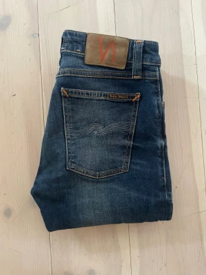 Mörkblå jeans från Nudie Jeans - Nudie jeans! Modell skinny lin! Jeansen är i fint skick! Och passar till mycket! Ny pris ca=2000kr, W28 L32, hör av er vid minnsta lilla fundering! Priset sitter ej fastspikat vid snabb affär! 