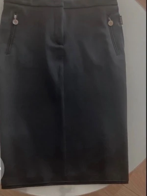 Moncler kjol Ny  - Stilren svart MONCLER pennkjol med två dragkedjor framtill och diskreta sömdetaljer. Kjolen har en klassisk, figurnära passform och är perfekt för en snygg och enkel look. Passar till många olika outfits och är lätt att matcha. Nypris över 5000 kr 