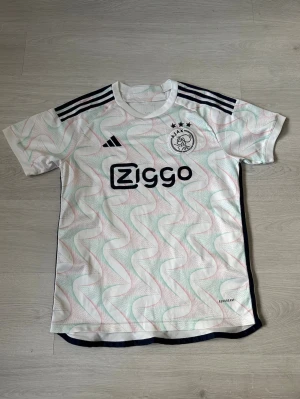 Ajax S - Säljer en snygg och stilren Ajax-tröja i fint skick – perfekt för både matchdagar och vardagsstil! ⚽ Tröjan är bekväm, av hög kvalitet och ett måste för alla fans av klubben.  Passa på att uppdatera din supporter-garderob eller ge bort en uppskattad present till någon som älskar fotboll!  👉 Kika gärna in min profil – jag säljer fler fotbollströjor i olika modeller och storlekar. 💥 Rabatt erbjuds vid köp av flera plagg!  Hör av dig vid frågor eller intresse! 