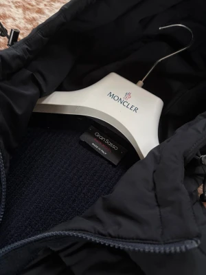 Mörkblå Gran Sasso Cardigan - Snygg mörkblå stickad cardigan från Gran Sasso, tillverkad i 100% ull. Tröjan har en klassisk, enkel design med grovstickad struktur och rund hals. Perfekt för dig som gillar stilrena och tidlösa plagg i garderoben. Perfekt till våren och kalla sommarkvällar. Nypris 7000 kr. Bara att höra av sig vid frågor// Carl