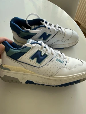 New Balance 550 vita/blå sneakers - Säljer ett par New Balance 550 sneakers i färgen White Blue Groove.. Skorna har en chunky sula, perforerade paneler och klassisk N-logga på sidan. Ovandelen är i läder och mesh för en sportig look. Perfekta för dig som gillar retrostil. Fick i julklapp och när de nu skulle sättas på upplevde jag dom möte för stora dessvärre så är i nyskick.