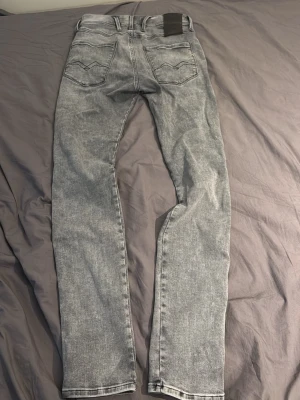 Grå tvättade jeans från Nudie Jeans - Säljer ett par grå tvättade jeans från Nudie Jeans med raka ben och klassisk femficksmodell. Jeansen har en snygg vintagekänsla och svart patch bak i midjan. Perfekta för dig som gillar en avslappnad men stilren look. Jätte fint skick kan diskutera pris vid snabb affär