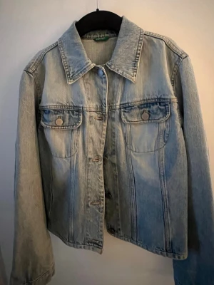Ljusblå klassisk jeansjacka - Snygg ljusblå jeansjacka med raka linjer och två bröstfickor med knappar. Jackan har en klassisk krage och knappstängning framtill. 