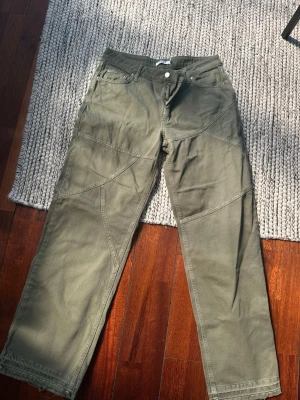 Khaki jeans från NA-KD - Säljer ett par khaki jeans från NA-KD med raka, vida ben och coola sömdetaljer. Storlek 40, använda 1 gång💚