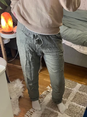 Gröna linnebyxor  - Säljer ett par gröna linnebyxor med bra och fint material som inte kommit till användning så mycket. De ser skrynkliga ut på bilderna men det går att fixa med strykjärn. De har även resår/snören som man kan dra åt midjan med. Materialet är 100% linne.
