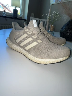 Adidas ultra boost - Säljer dessa riktigt snygga adidas ultra boost cream white 1.0 riktigt fräscha och sköna inför sommaren nu. Inga defekter på skorna förutom den blåa fläcken i skon Tyvvär som hände pågrund av färg.  Har inte tvättat dom på tyget så ni kan göra dom mer fräschare. Kostade cirka 3000 nypris. Ingen box då ja Tyvvär slängt.