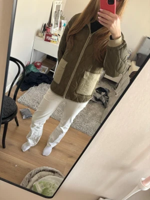 Tvås sidig grön quiltad jacka - Quiltad jacka i olivgrönt med kontrasterande beige fickor . Jackan har dragkedja framtill, två stora fickor och avslappnad passform. Perfekt för lager-på-lager och streetstyle.