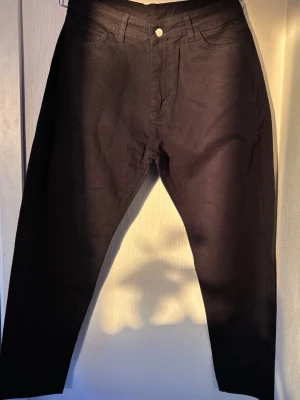 Svarta raka jeans med hög midja - Snygga svarta jeans med rak passform och hög midja. Klassisk femficksmodell med knapp och dragkedja framtill. Jeansen har en stilren look och passar perfekt till en trendig vardagsoutfit. Materialet känns mjukt och följsamt.