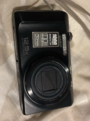 Svart Casio Exilim digitalkamera - Säljer en svart Casio Exilim digitalkamera med 12,5x optisk zoom, 10,1 megapixlar och HD Movie-funktion. Kameran har en kompakt design med inbyggd blixt och tydliga knappar. Perfekt för dig som vill ha en smidig kamera att ta med överallt.